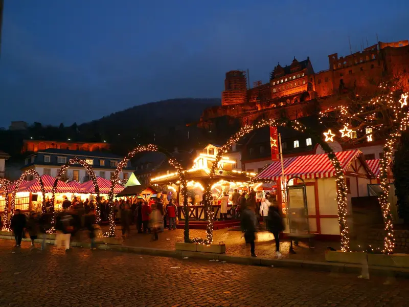Weihnachtsmarkt in der Heidelberger Altstadt am Abend mit beleuchtetem Schloss